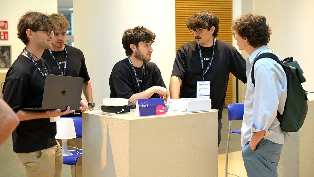 The Dory stand at the B4i Investor Day, with Dory and its box on the table, during a conversation with a guest.